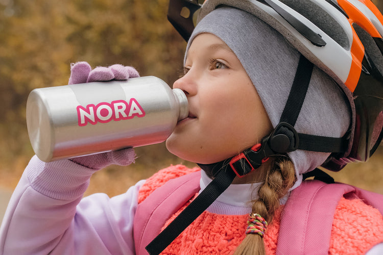 Girl drinking out of her favorite bottle with a vinyl identification sticker attached: Personalized bottle label with child's name, adding a touch of ownership and uniqueness to her favorite drinking container.